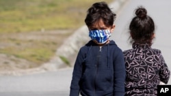 Deca migranata nose maske kako bi se zaštitila od zaraze Kovidom 19, tokom vakcinacije u centru za izbeglice u Krnjači, u Beogradu, 26. marta 2021. Srbija je započela sa vakcinacijom migranata. (Foto: AP)