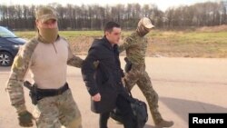 Mwanajeshi wa zamani wa Marekani Trevor Reed akishindikizwa kwenye ndege na maafisa wa Russia mjini Moscow, kama sehemu ya kubadilishana wafungwa kati ya Marekani na Russia, April 27, 2022. Picha ya Reuters
