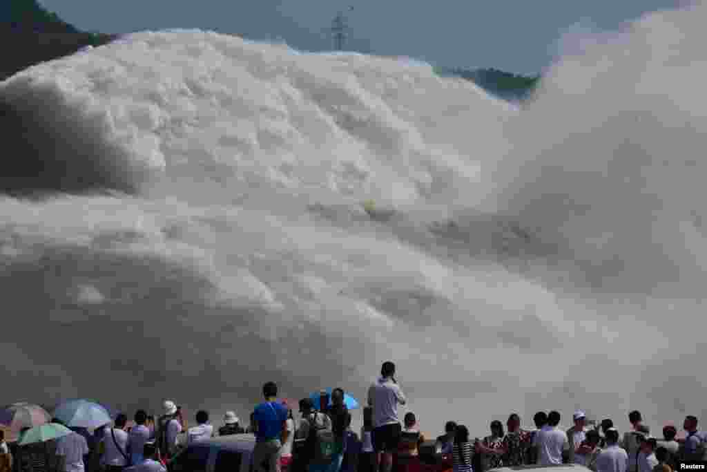 Para pengunjung mengamati semburan air dari waduk Xiaolangdi di Sungai Kuning di Luoyang, Henan, China.