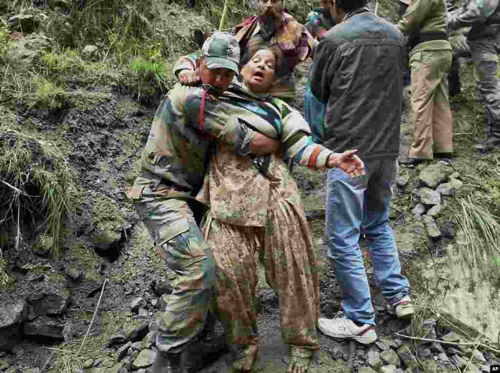 An Indian soldier carries a stranded woman pilgrim to a safer area in Chamoli district, in the northern Indian state of Uttarakhand, June 18, 2013.