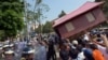 People carry a giant model of a house toward police as they protest government-sanctioned evictions, World Habitat Day, Phnom Penh, Oct. 10, 2013.