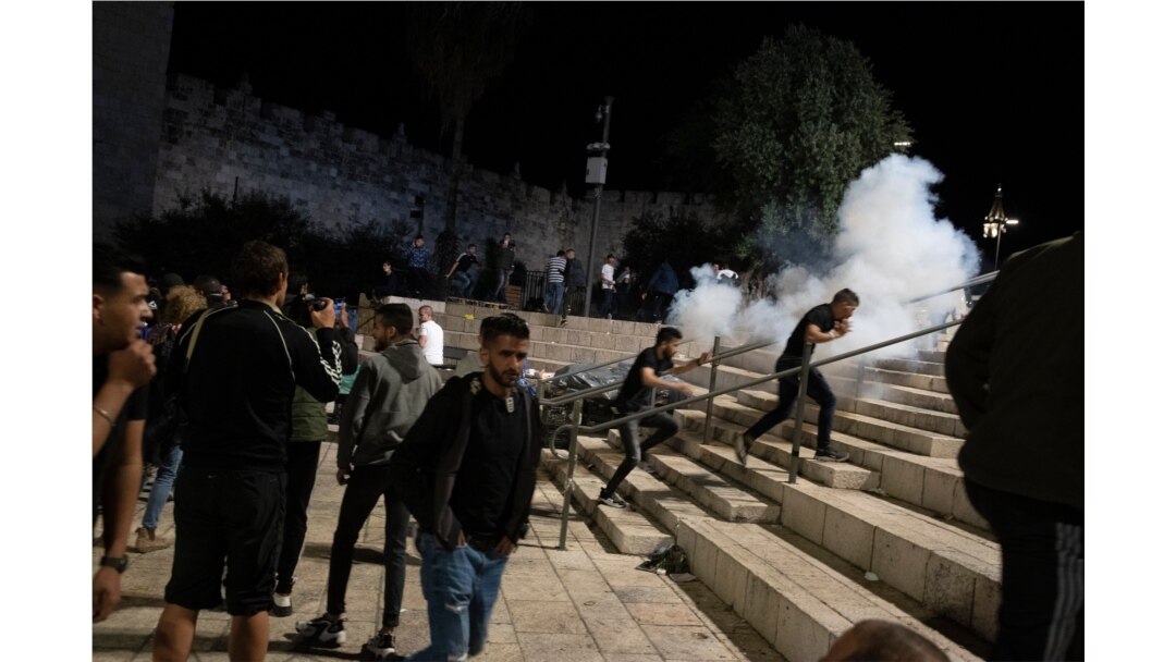 Wapalestina wanajihami kutokana na guruneti zilizofyatuliwa na polisi wa Israeli wakilenga kuwasambaza Wapalestina waliokuwa wamekusanyika katika lango kubwa la Damascus kuingia Mji wa Zamani wa Jerusalem baada ya mapambano kutokea katika viwanja vya Msikiti wa Al-Aqsa Mei 7, 2021.