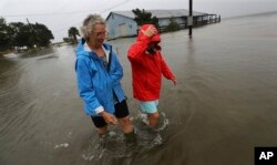 Dos residentes de St. Mary, en Georgia, caminan cerca de sus casas el 4 de septiembre de 2019, luego del paso del huracán Dorian. Curtis Compton/Atlanta Journal-Constitution via AP.