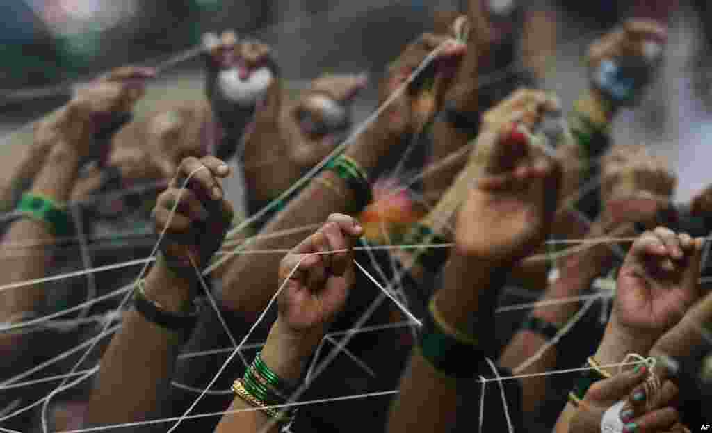 Indian Hindu married women tie cotton threads around a Banyan tree as they perform rituals on the occasion of Vat Savitri festival in Mumbai.