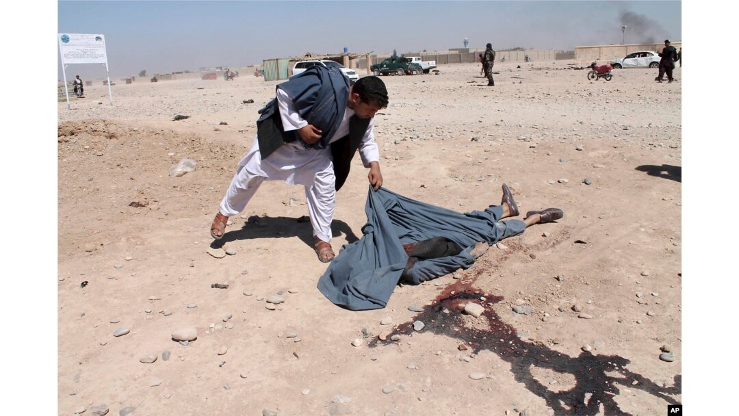 An Afghan man looks at the dead body of a victim of suicide attack in Lashkar Gah the capital of southern Helmand province, Oct. 10, 2016.