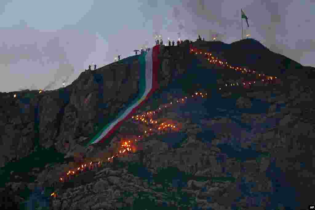 Warga Kurdi Irak dengan spanduk raksasa dalam warna bendera Kurdi merayakan Nawruz, atau tahun baru, di Dahuk, 260 km (430 kilometer) di sebelah barat laut Baghdad, Irak. Perayaan Nawruz berakar pada masa Zoroaster untuk menandai datangnya musim semi dan perayaan awal tahun baru bagi orang Kurdi seluruh dunia.