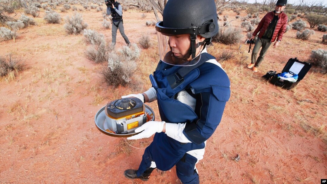 In this photo provided by the Japan Aerospace Exploration Agency (JAXA), a member of JAXA retrieves a capsule dropped by Hayabusa2 in Woomera, southern Australia, Dec. 6, 2020.