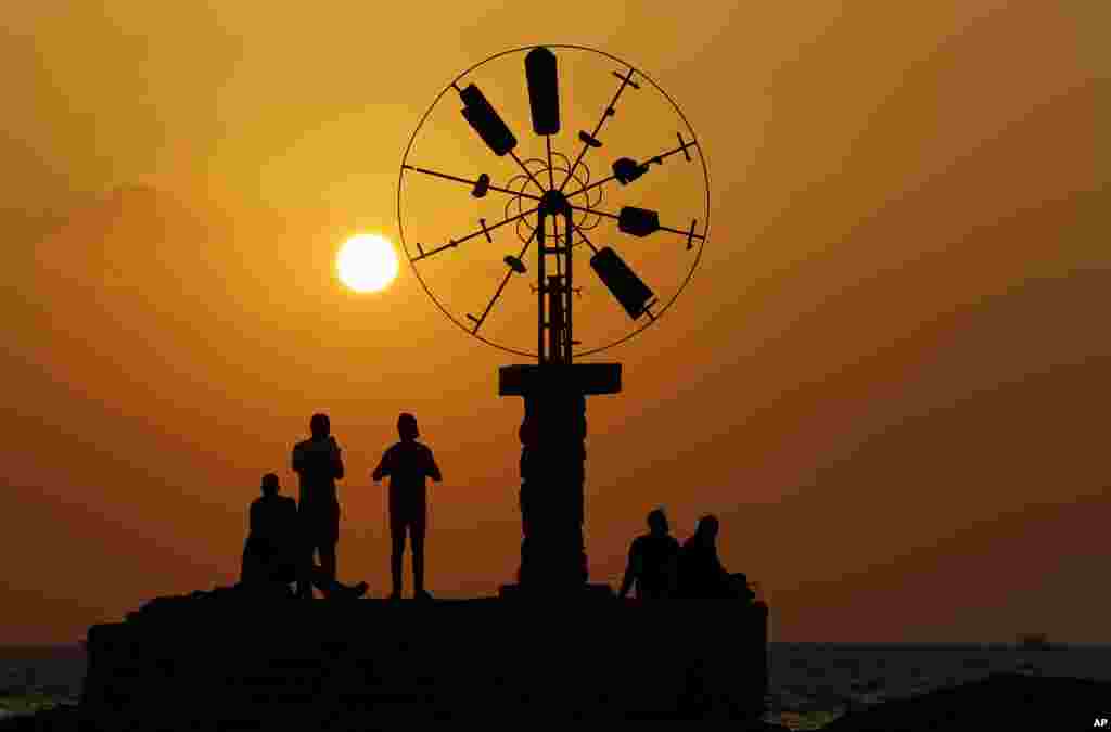 People watch the sunset, on the coast of Tripoli city, north of Lebanon.