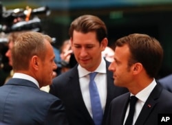 European Council President Donald Tusk, left, speaks with Austrian Chancellor Sebastian Kurz, center, and French President Emmanuel Macron during a round table meeting at an EU summit in Brussels, Oct. 17, 2018.