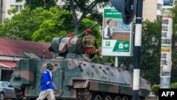 Un homme passe un char de l'armée zimbabwéenne où les soldats régulent le trafic routier, à Harare, au Zimbabwe, le 15 novembre 2017. 