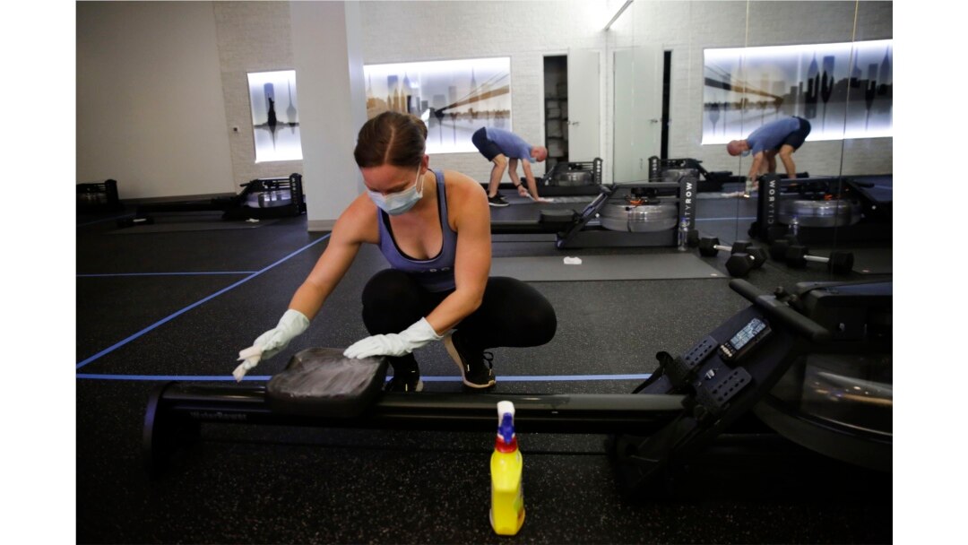 Employee of CITYROW Atlanta Midtown, Ellie Klarl, cleans the equipment after a class as gyms reopen with limited members on Saturday, May 16, 2020, amid the COVID-19 virus in Atlanta.