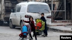Niños empujan coches con sus pertenencias mientras huyen hacia los últimos enclaves rebeldes de Alepo, en Siria. Dec. 12, 2016.