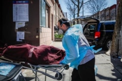 Employees deliver a body at Daniel J. Schaefer Funeral Home, Thursday, April 2, 2020, in the Brooklyn borough of New York.