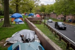 Vehicles exiting from an expressway drive past a homeless encampment near the State Department in downtown Washington, on Friday, April 16, 2021. (AP Photo/Amanda Andrade-Rhoades)