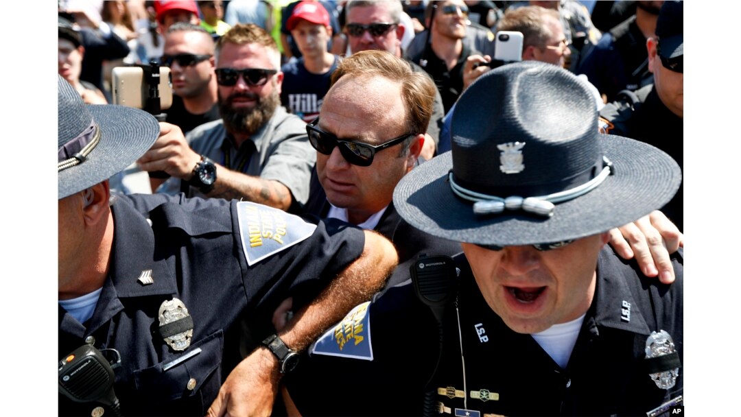 FILE - Alex Jones (C), an American conspiracy theorist and radio show host, is escorted out of a crowd of protesters after he said he was attacked in Public Square on July 19, 2016, in Cleveland, during the second day of the Republican convention.