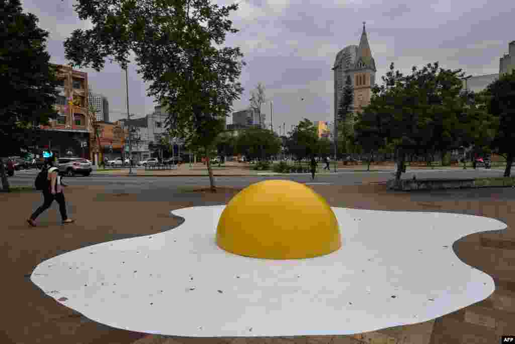 A person walks by an urban intervention called "Eggcident" — a warning for the severity of global warming — by Dutch artist Henk Hofstra during the annual "Virada Sustentavel SP" event, in Sao Paulo, Brazil.