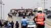 A polícia observa as pessoas a reunirem-se durante a manifestação para protestar contra o aumento do custo de vida, a corrupção em todo o país e para exigir a realização de eleições locais, em Luanda, a 20 de Março de 2021.