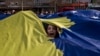 Arhiva - Devojka proviruje kroz prorez na džinovskoj zastavi Kosva tokom proslave devete godišnjice nezavisnosti u glavnom gradu Prištini, Kosovo, 17. februara 2017.