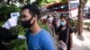 Un agente de seguridad verifica la temperatura de las personas que usan mascarillas para ayudar a frenar la propagación del coronavirus mientras hacen fila.