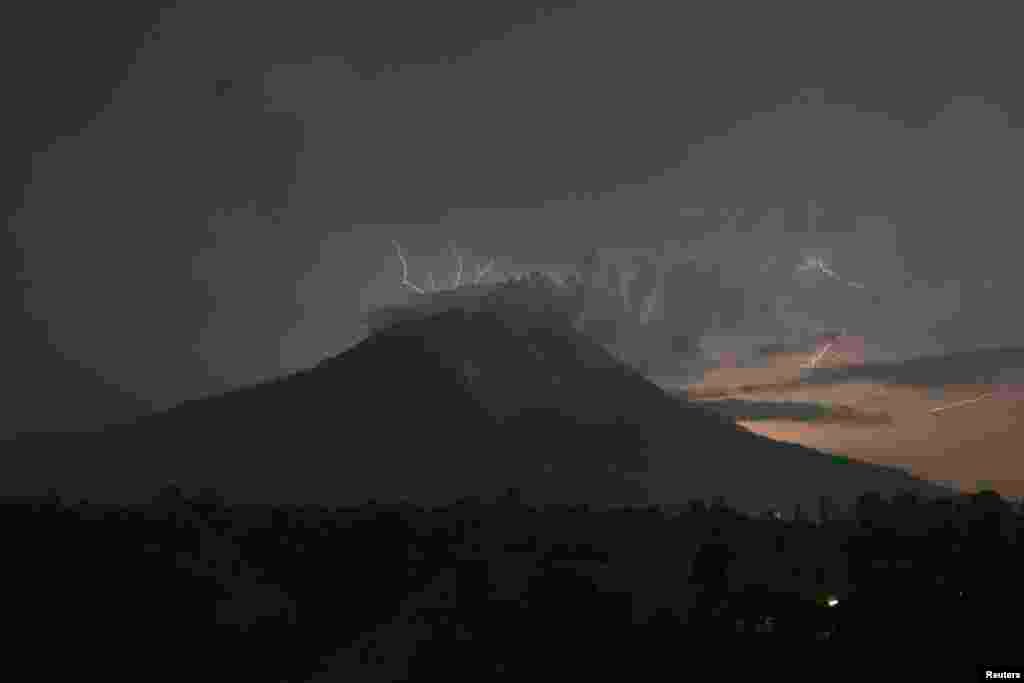 Kilatan petir menyambar sementara Gunung Sinabung mengeluarkan abu vulkanik dan lava panas, di desa Simpang Empat, Kabupaten Karo, Sumatera Utara.