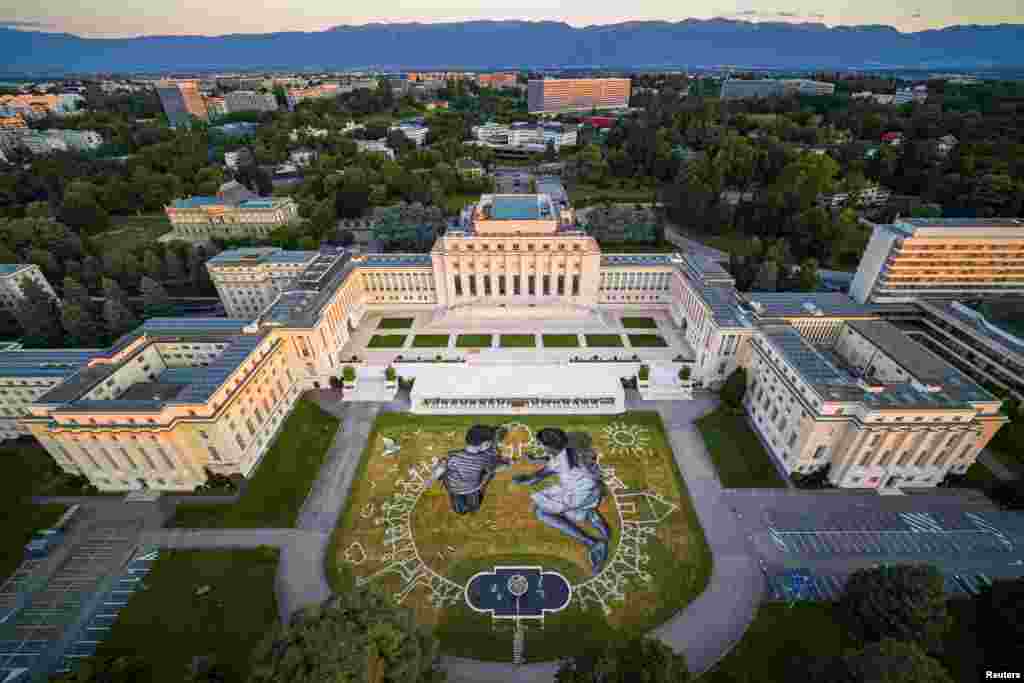 A view of artwork called "World in progress" by French artist Saype depicts two children as they draw a tree to commemorate the 75th anniversary of the founding of the United Nations on the lawn of its European headquarters, in Geneva, Switzerland.