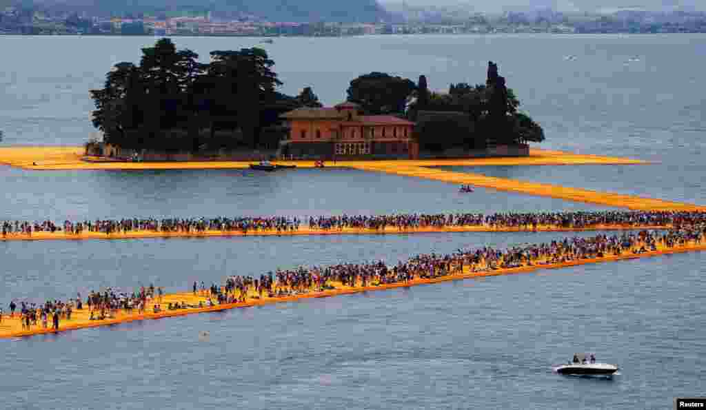 Warga berjalan pada instalasi 'Pelabuhan Mengambang' karya seniman Bulgaria Christo Vladimirov Yavachev, di dekat Sulzano, Italia utara.