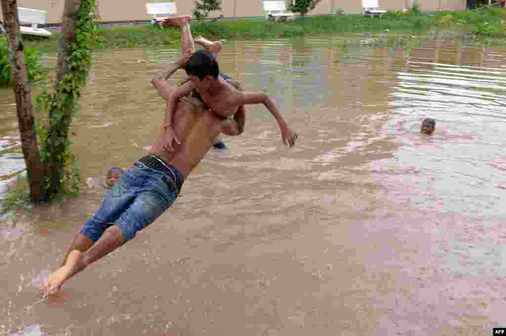Seorang laki-laki membawa seorang bocah laki-laki, melompat ke dalam banjir di pinggiran kota Phnom Penh, Kamboja.