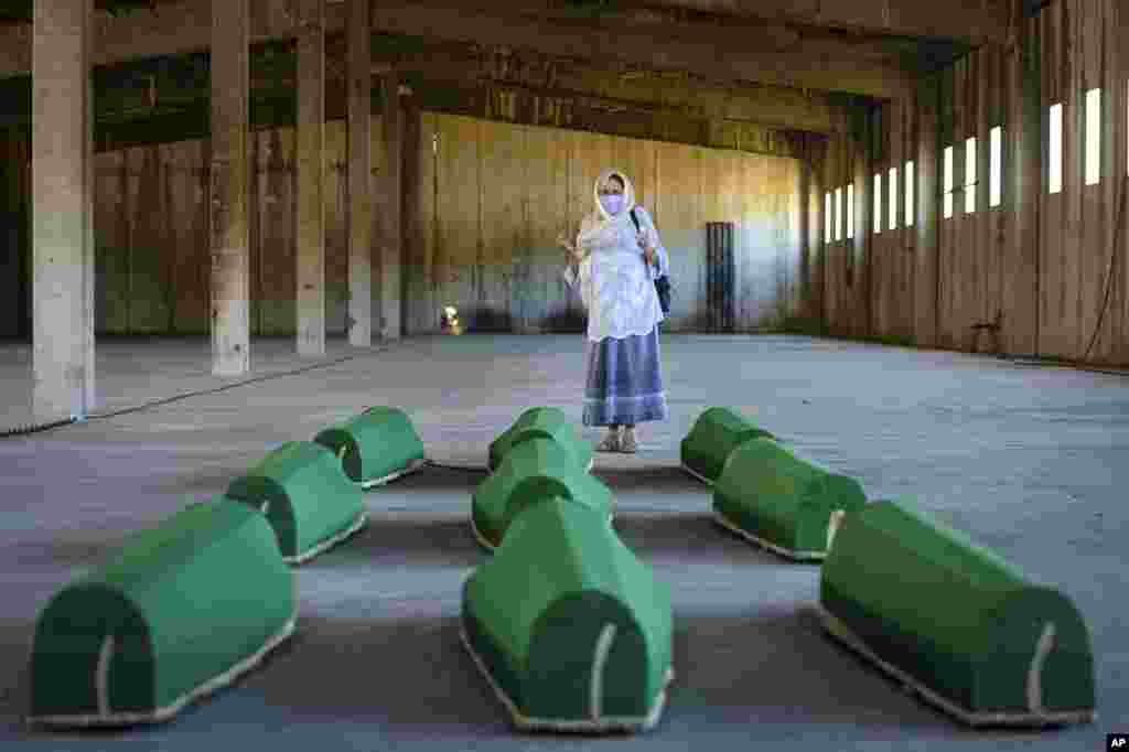 A woman prays next to coffins at the former U.N. base in Potocari, Bosnia. Nine newly found men and boys will be laid to rest when Bosnians commemorate 25 years since Srebrenica was overrun by Bosnian Serb forces, in Europe's worst post-WWII massacre.