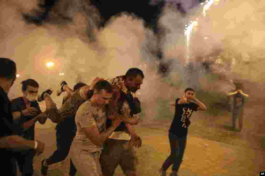Protesters carry a wounded man during clashes with police after the presidential election in Minsk, Belarus.