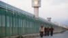 FILE - Workers walk by the perimeter fence of what is officially known as a vocational skills education center in Dabancheng in Xinjiang Uighur Autonomous Region, China, Sept. 4, 2018. 