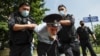 Police officers detains a protester, center, dressed as a Russian police officer before a court hearing of the New Greatness group who are charged with the organization of an extremist association in Moscow, Russia, Aug. 6, 2020.