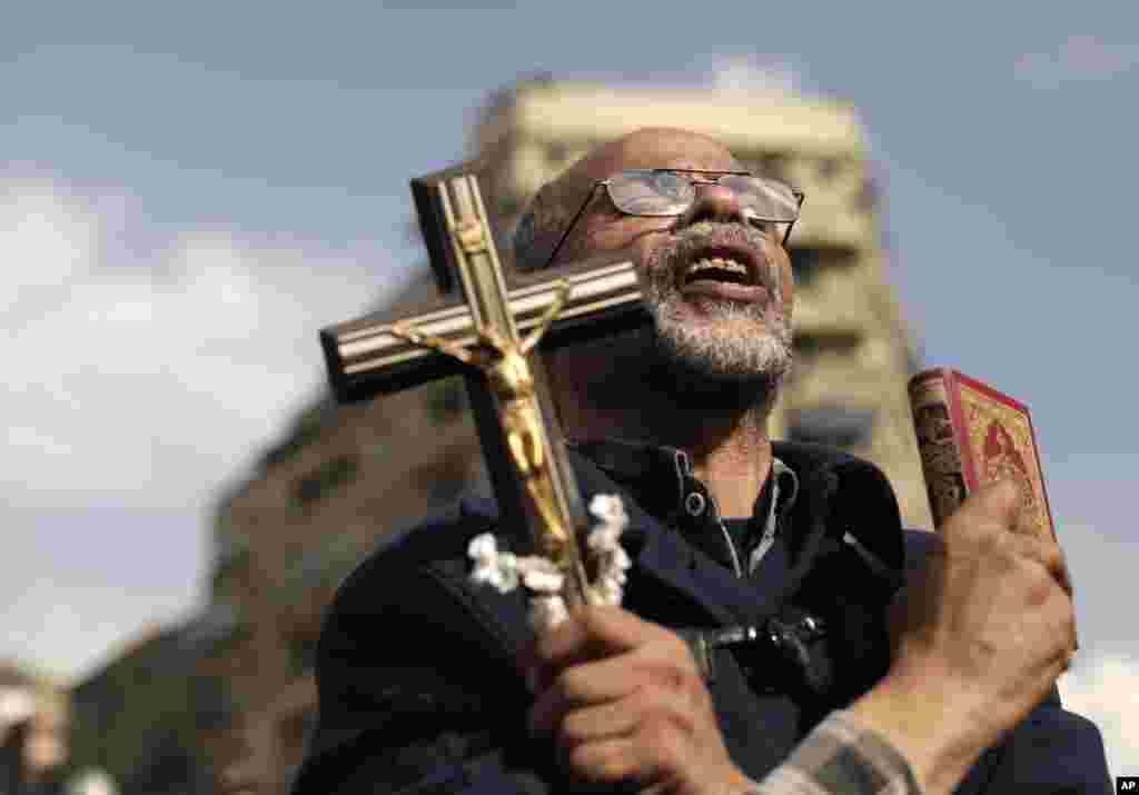 An Egyptian protester chants slogans and holds a cross and a Quran in Tahrir Square, Cairo, Egypt, November 23, 2012.