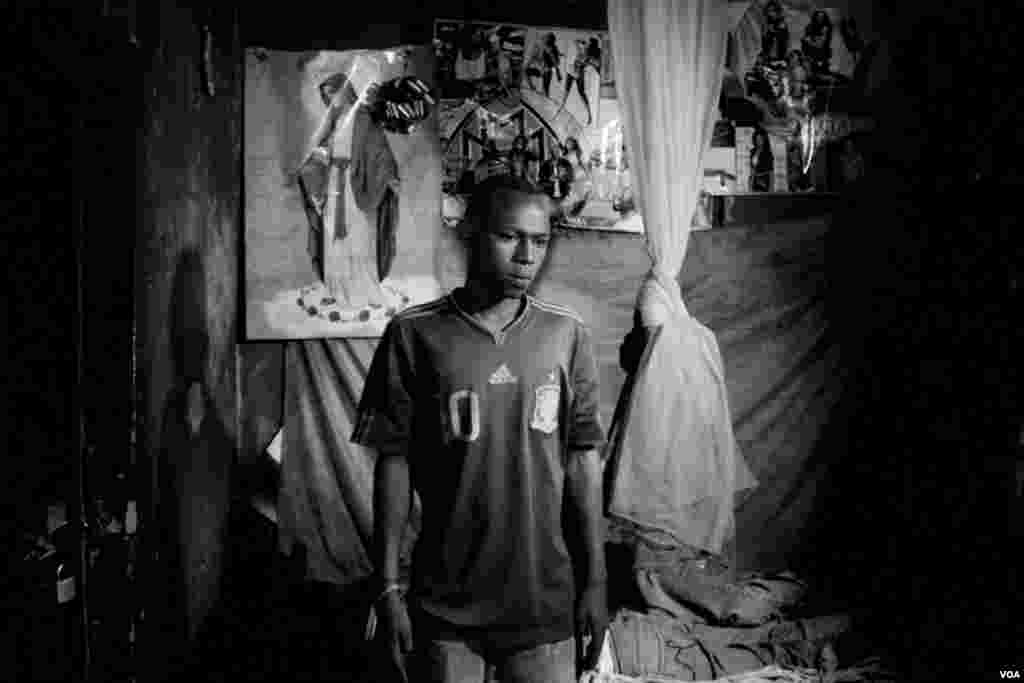 Kuitonda David, 24, di kamarnya di tempat bilyar dimana ia bekerja. Ia bergantian tidur dalam satu ranjang di kamarnya dengan teman kerjanya, Nzamwita Afrodis, yang hidup dengan HIV, di Giporoso, Kigali, Rwanda. (VOA/Hamada Elrasam)