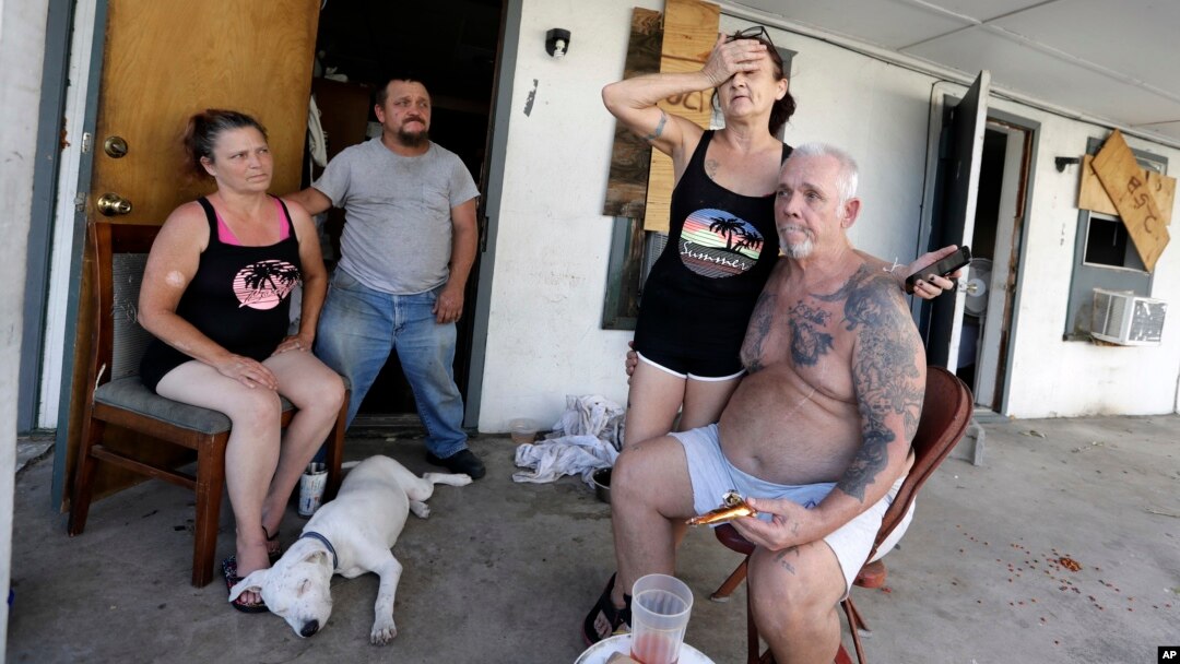 Debra Harmon holds her head as she recall riding out Hurricane Harvey in their apartment they lack of resources they have available including electricity, Aug. 29, 2017, in Aransas Pass, Texas. 