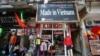 FILE - Vendors sit outside a shop selling clothes in Hanoi, Oct. 3, 2014.
