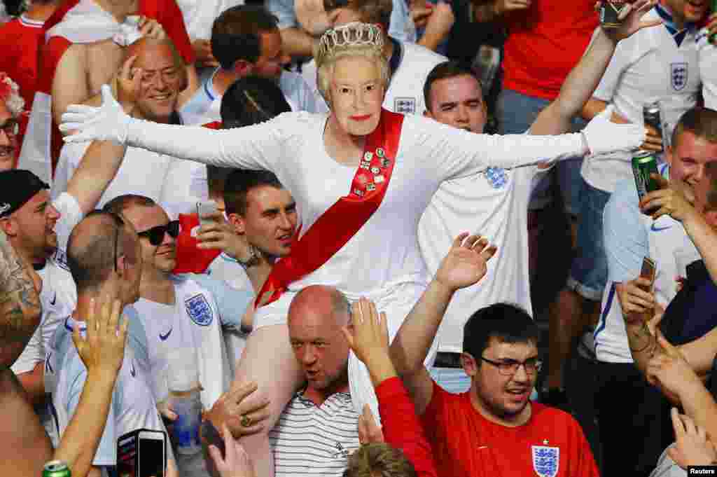 Seorang pendukung timnas Inggris mengenakan topeng Ratu Elizabeth II menjelang pertandingan Euro 2016 melawan timnas Slovakia di Saint Etienne, Perancis.