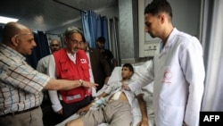 Wasu Ma'aikatan Kungiyar Red Cross da wani majinyaci a kwance a gadon asibiti.