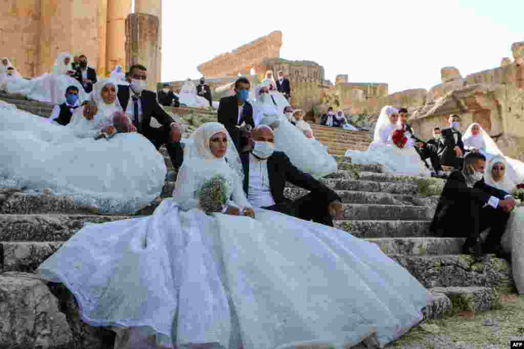 Lebanese couples, wearing protective face masks, sit on the steps during a group wedding at the Temple of Bacchus at the historic site of Baalbek in Lebanon's eastern Bekaa Valley.