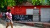 Una mujer pasa frente a una casa con un grafiti del grupo guerrillero ELN, en el municipio de El Zulia, cerca de Cúcuta, Colombia, el 4 de julio de 2023. (Foto por Schneyder MENDOZA / AFP)