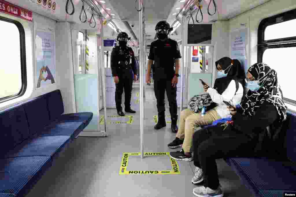 Auxiliary police officers wearing 'Smart Helmet', a portable thermoscanner that can measure the temperature of passengers at a distance, patrol inside a commuter train, in Kuala Lumpur, Malaysia.