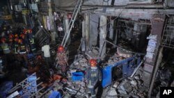 Rescuers stand amid the debris after a blast at a market in Dhaka, Bangladesh, Sunday, June 27, 2021. (AP Photo)