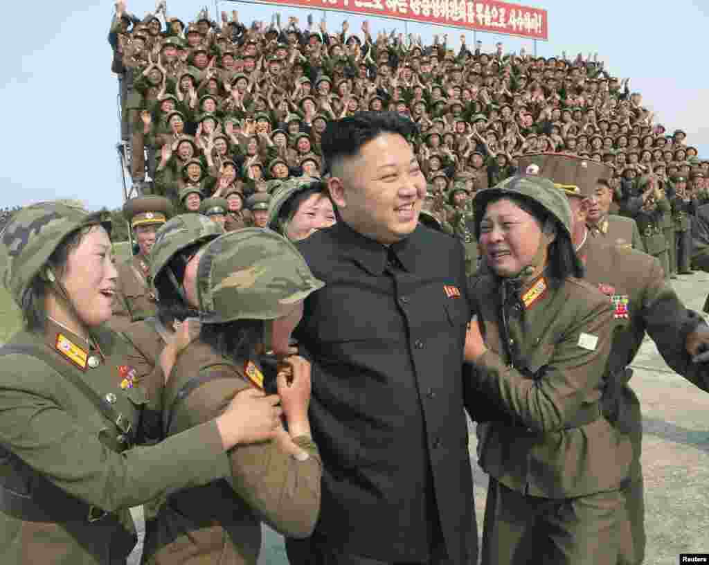 Pemimpin Korea Utara, Kim Jong Un bersama para tentara perempuan Korut yang bekerja di sub unit peluncuran roket dalam sebuah acara di Pyongyang. 