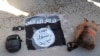 Bendera dan tas milik anggota pasukan ISIS dikumpulkan setelah mereka berhasil ditangkap oleh Pasukan Demokratik Suriah dalam sebuah serangan di penjara Gweiran di Hassakeh, Suriah, pada 21 Januari 2022. (Foto: Kurdish-led Syrian Democratic Forces, via AP)