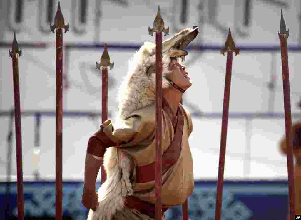 A performer wearing a wolfskin strikes a pose during the Naadam Festival in Ulaanbaatar, Mongolia. Mongolians celebrate the anniversary of Genghis Khan's march to world conquest on July 11, with the annual Naadam sports festival featuring traditional Mongolian events, including wrestling, archery, and horse racing. 