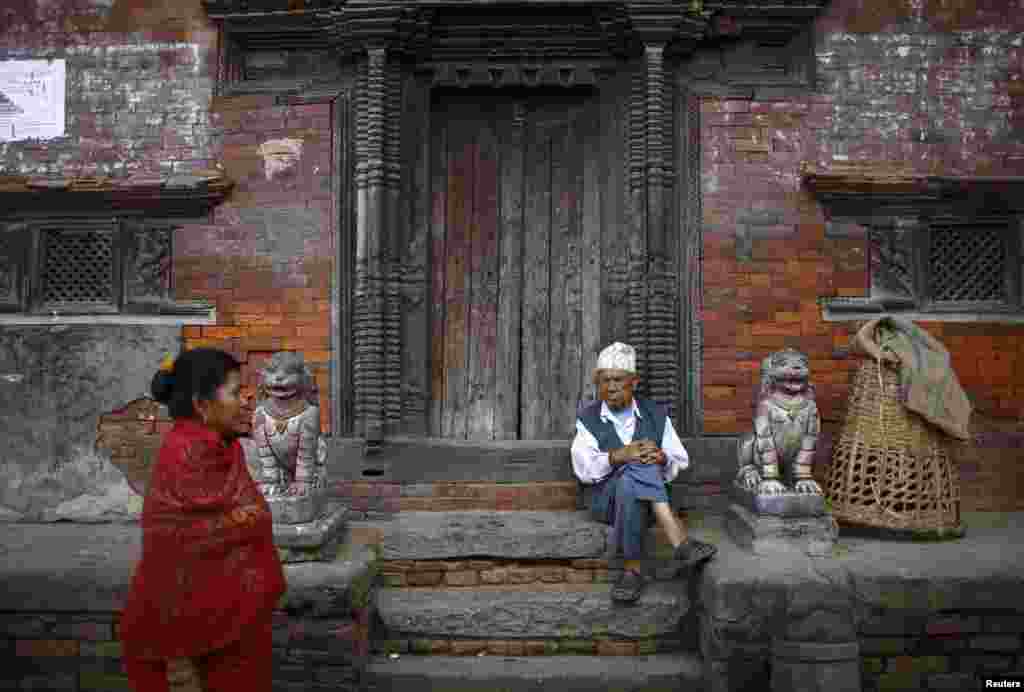Seorang pria duduk di depan pintu sebuah kuil di kota kuno Bhaktapur, dekat ibukota Nepal, Kathmandu.