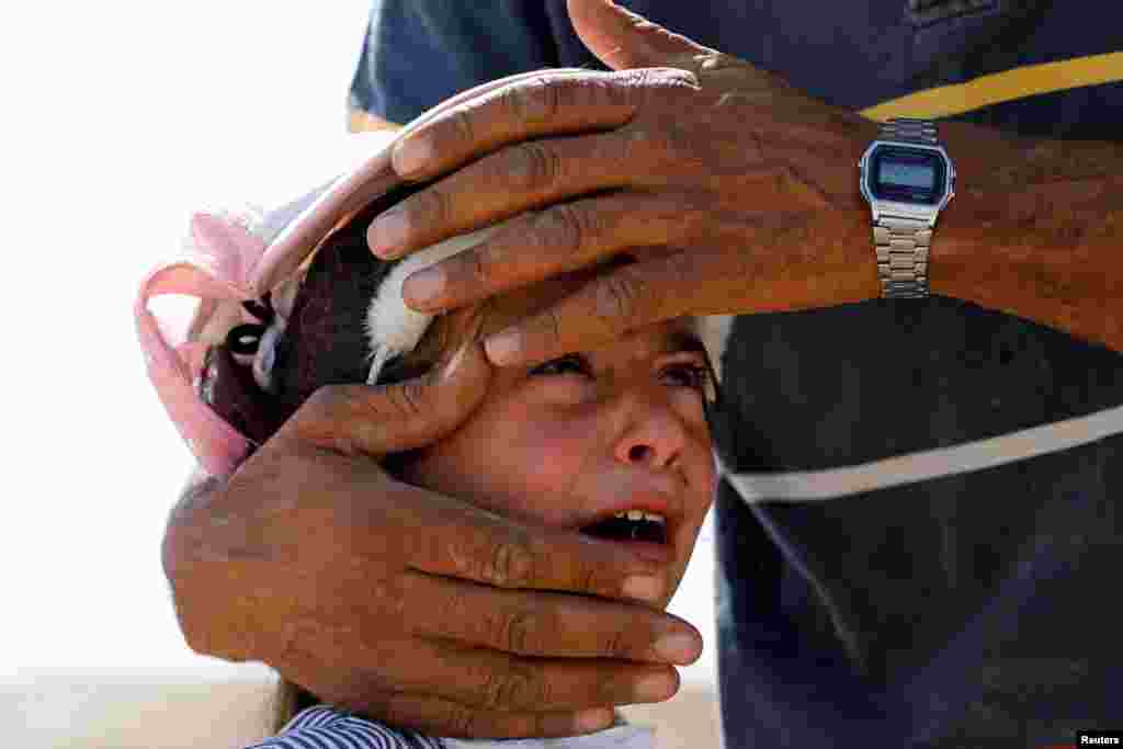 A Palestinian girl cries as she is comforted by her uncle after Israeli forces demolished her family's house near Hebron in West Bank.