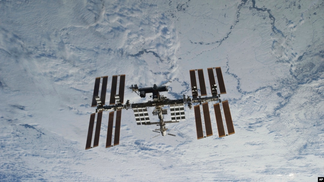 In this NASA photo, backdropped against clouds over Earth, the International Space Station is seen from Space Shuttle Discovery as the two orbital spacecraft accomplish their relative separation on March 7, 2011. (NASA via AP)