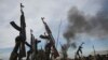 Rebel fighters hold up their rifles as they walk in front of a bushfire in a rebel controlled territory in Upper Nile State, South Sudan, Feb. 13, 2014. 