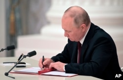 El presidente ruso, Vladimir Putin, firma un documento que reconoce la independencia de las regiones separatistas en el este de Ucrania en el Kremlin en Moscú, el 21 de febrero de 2022.