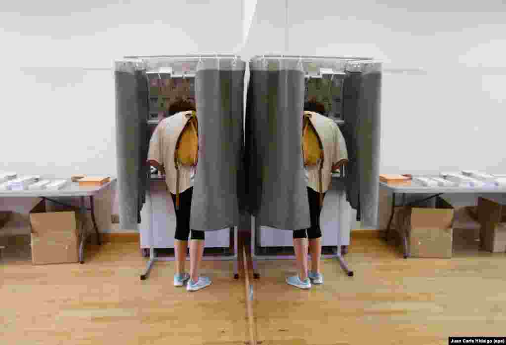 A woman casting her vote is reflected in a mirror at a polling station during the general elections at in Madrid, Spain. More than 36 million Spaniards went to the polls for the second time, to vote in general elections after no party had the 176 seats required to form a government in the first vote held on Dec. 20, 2015. 
